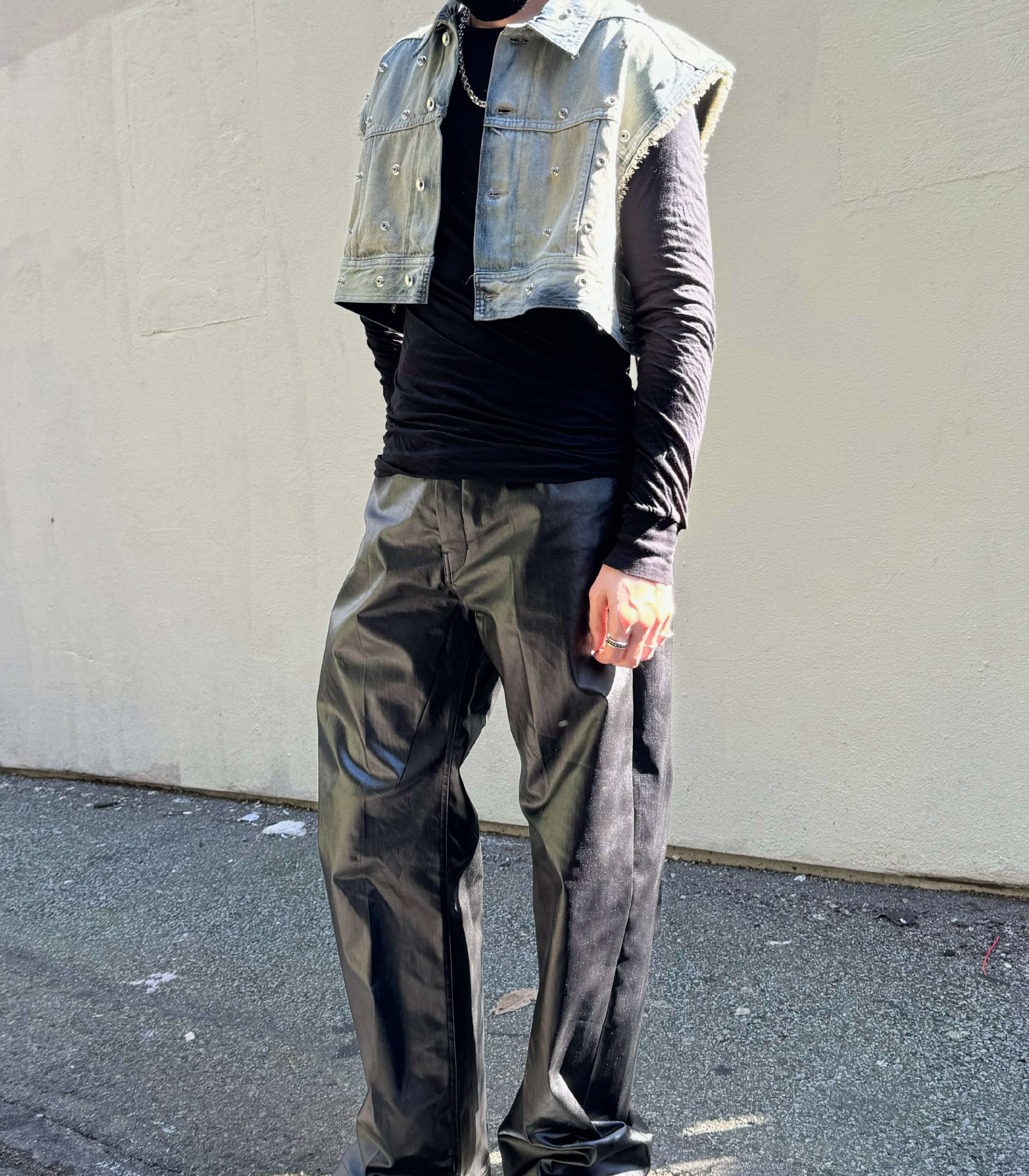Person wearing a Rick Owens DRKSHDW denim vest and geth pants against a plain wall.