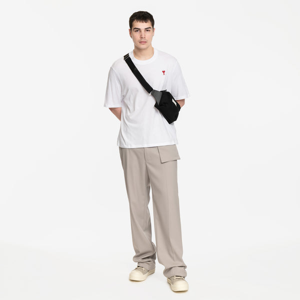 model wearing white tshirt with Margiela crossbody bag, with MM6 gray trousers and rick owens high top sneakers in pearl