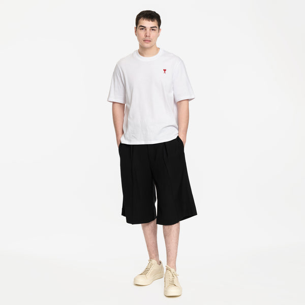 model wearing bermuda shorts with white ami tshirt and white rick owens vintage sneakers