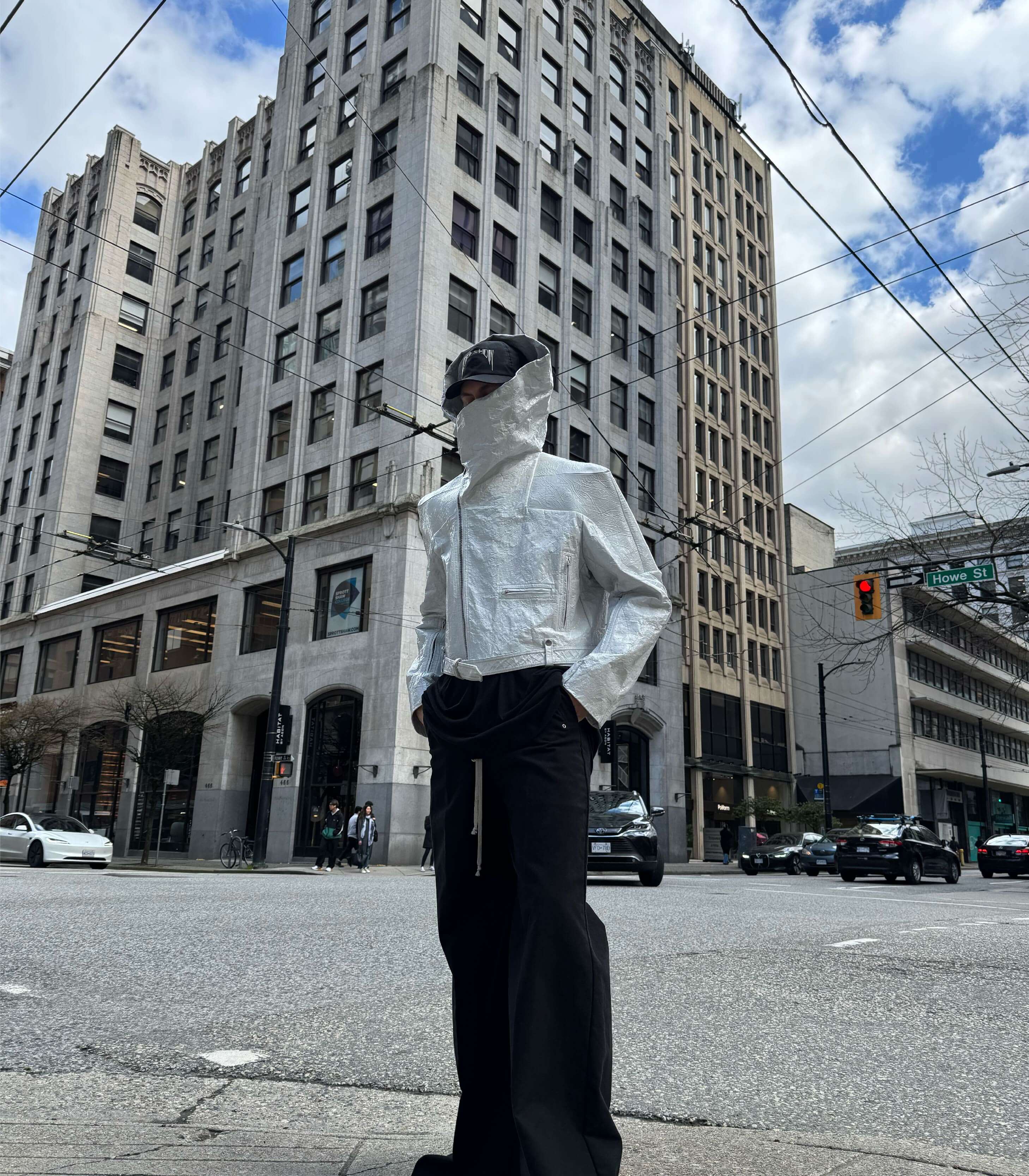 Person wearing a Rick Owens DRKSHDW jacket and black pants on a city street with tall buildings in the background.
